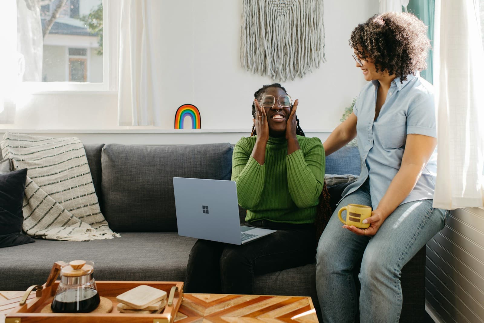 Two friends celebrating good news at a laptop