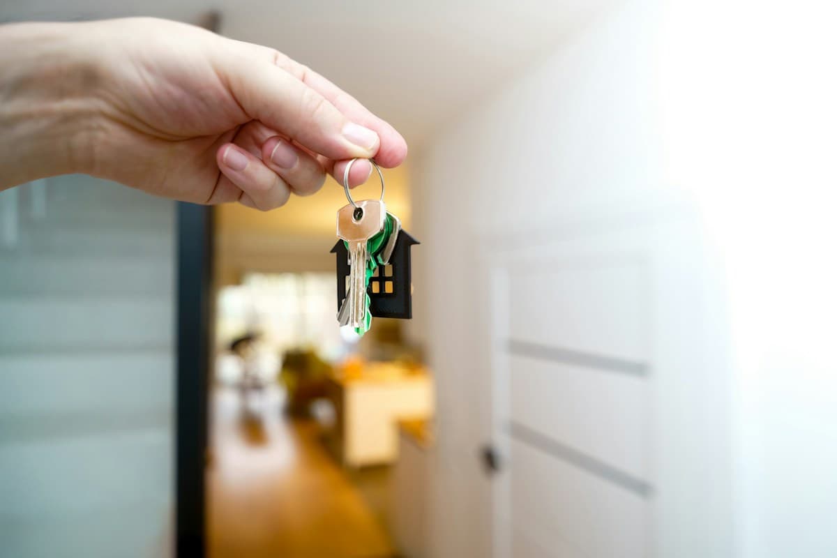 A hand holding out a set of house keys